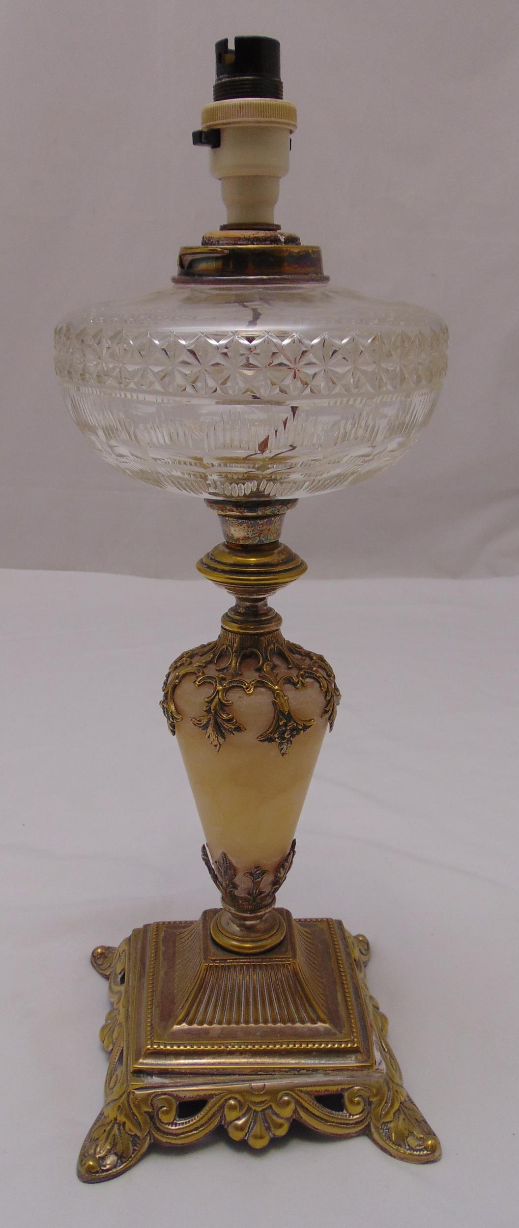 A Victorian oil lamp base with glass reservoir on raised square base, stylised leaf feet,