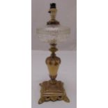 A Victorian oil lamp base with glass reservoir on raised square base, stylised leaf feet,