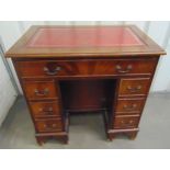 A rectangular mahogany kneehole desk with tooled leather top and brass swing handles on bracket