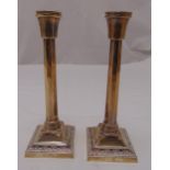 A pair of hallmarked silver table candlesticks of panelled columnular form on raised square bases