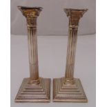 A pair of hallmarked silver Corinthian column table candlesticks on stepped square bases