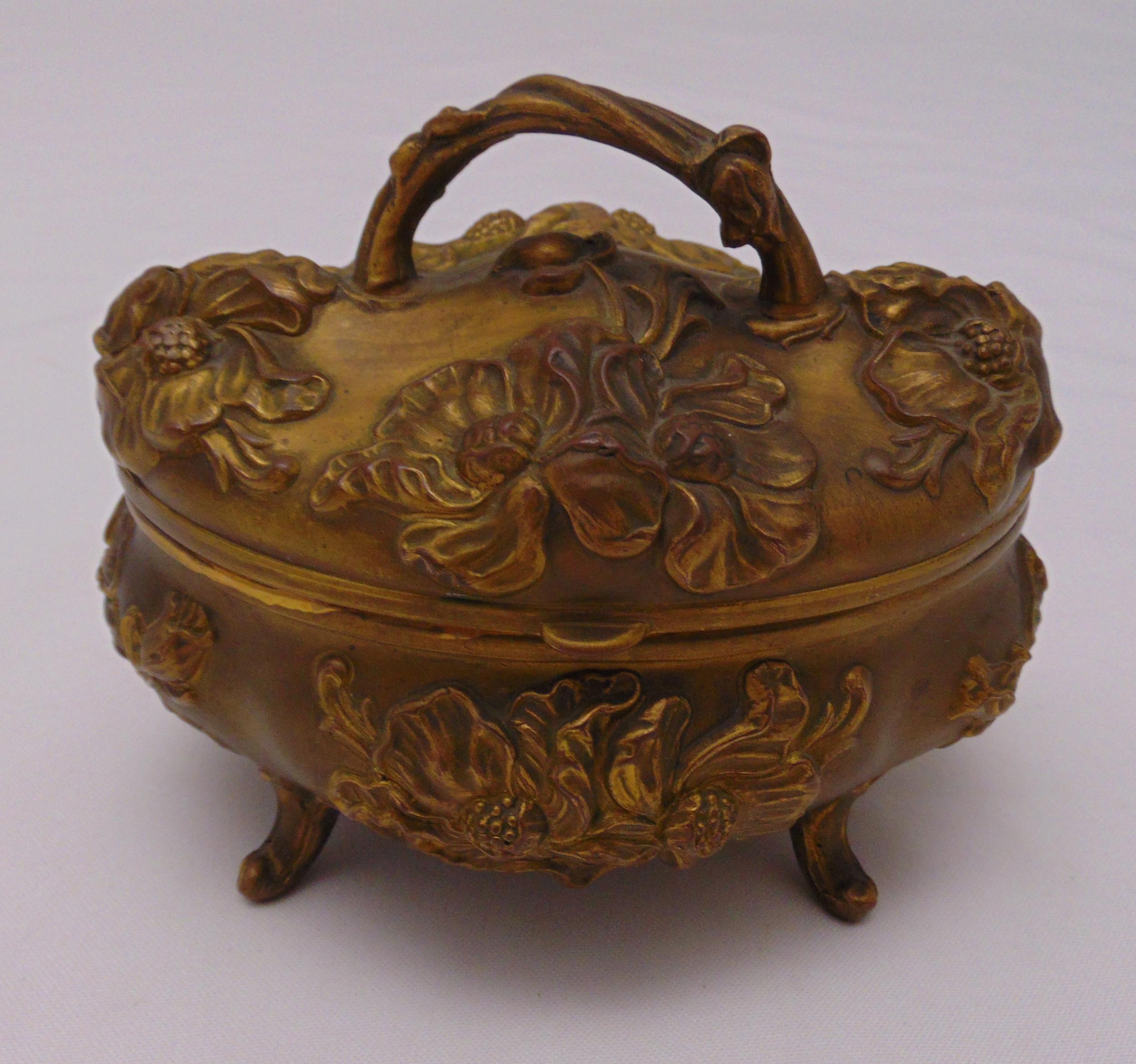 An oval gilt metal jewellery casket with hinged cover on four scroll feet, 12 x 14 x 11cm