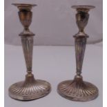 A pair of hallmarked silver table candlesticks tapering oval, fluted with beaded borders, London