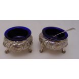 A pair of Victorian hallmarked silver salts, cauldron form chased with flowers and leaves with