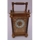 A late 19th century brass carriage clock with fluted columns hinged handle, the enamel dial with