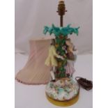 A Meissen style figural table lamp in the form of a man and lady standing under a tree mounted on