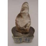An oriental carved rock crystal figurine paperweight mounted on a shaped blue and white ceramic