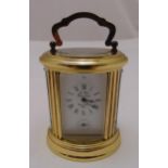 A L'pee France miniature brass shaped oval carriage clock white enamel dial, Roman numerals and
