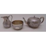 A Victorian hallmarked silver three piece teaset in the Indian style, profusely chased with stylised