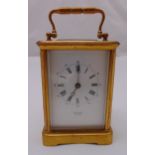 A brass carriage clock of customary form with chime, white enamel dial with Roman numerals by