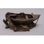 A silver plated model of a rowing boat on naturalistic rocky base, 8 x 19 x 10cm