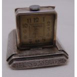 An Art Deco white metal Orator miniature travel clock with white dial and Arabic numerals