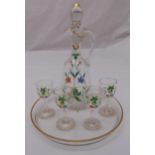A painted liqueur decanter with drop stopper and scroll handle, four matching shot glasses and a