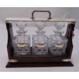A three bottle Tantalus with cut glass decanters and three hallmarked silver wine labels, 32.5 x