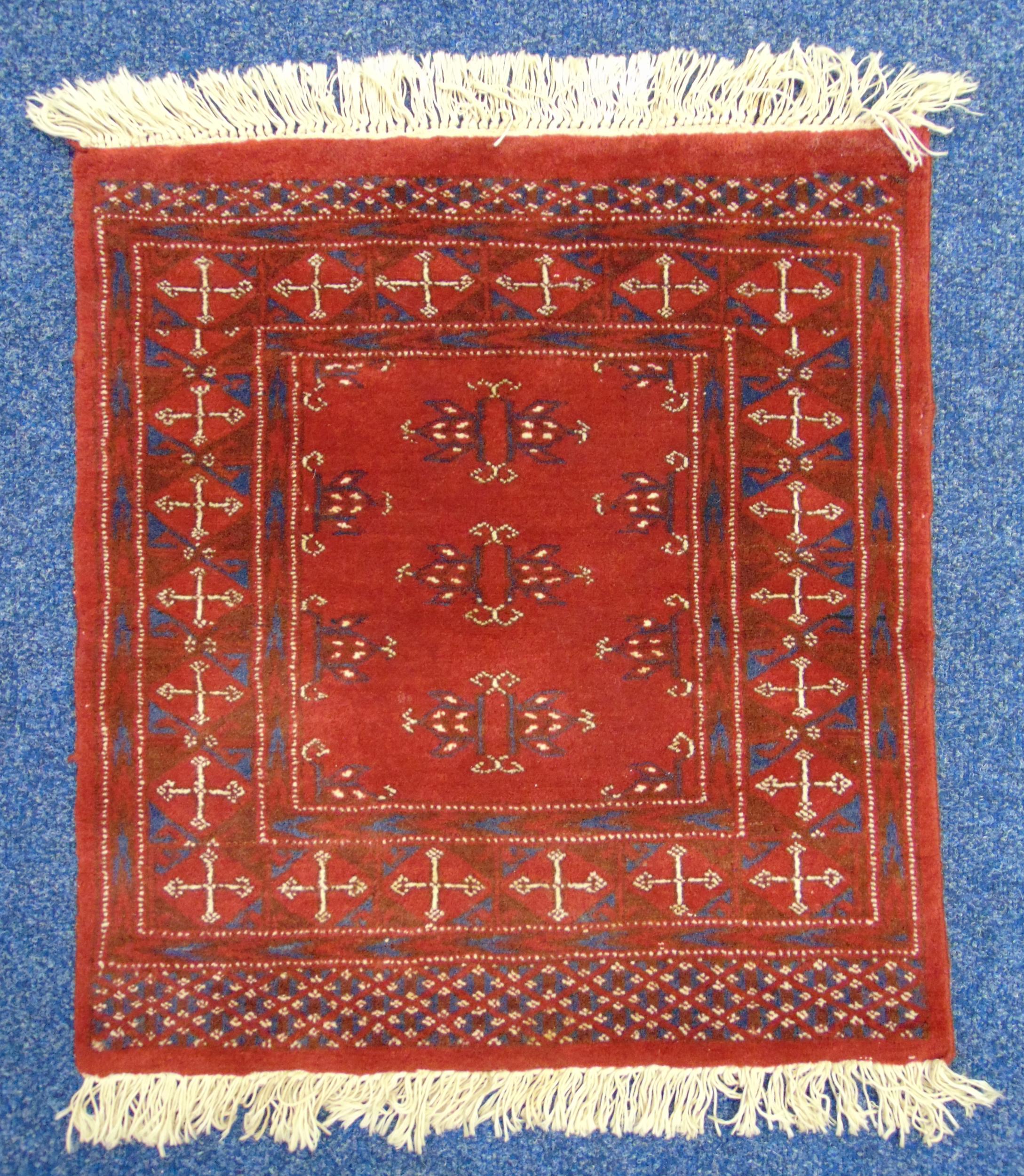 A Middle Eastern red ground prayer mat with repeating geometric patterns, 66 x 60.5cm