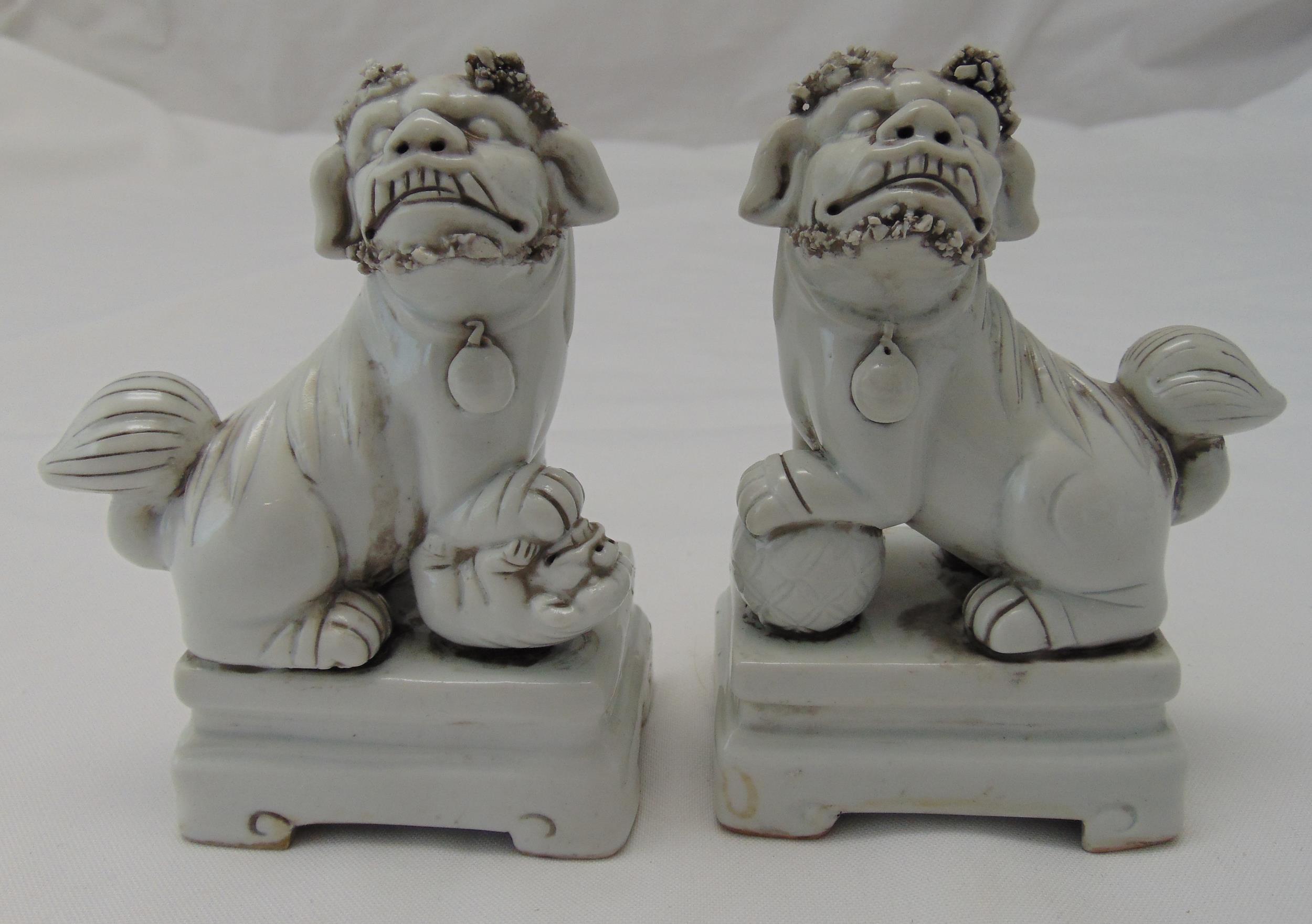 A pair of Chinese blanc de chine of dogs of foe on raised rectangular bases, 12 x 8.5 x 4cm each