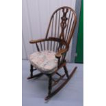 An oak rocking chair, spindle back, scrolling arms on turned supports