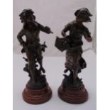 A pair of spelter figurines of a boy and girl carrying baskets, mounted on raised circular