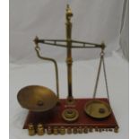 A brass balance scale on rectangular mahogany stand with weights