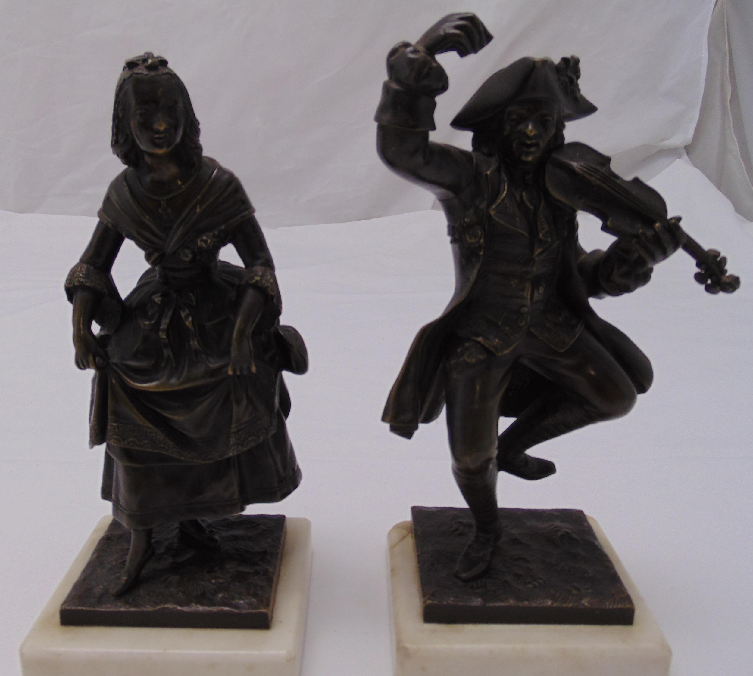 A pair of bronze figurines of a man playing a violin and a lady dancing both on raised white