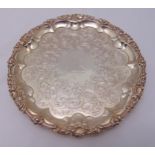 A William IV hallmarked silver circular salver with shell and leaf border, flat chased with flowers,