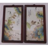 A pair of oriental ceramic enamel plaques decorated with flowers and birds in hardwood frames, circa