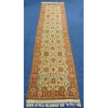 A wool runner, cream ground with repeating pattern and red border, 3.5m x 90cm