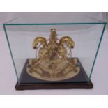 A gilded metal skeleton clock mounted on a rectangular wooden plinth with detachable glass case to