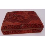 An oriental rectangular cinnabar lacquer box profusely carved with figures, trees, scrolls and