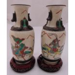 A pair of Chinese crackle glazed vases decorated with mounted warriors on carved wooden circular