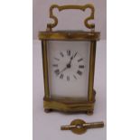 A brass carriage clock of customary form, the white dial with Roman numerals, swing handle and