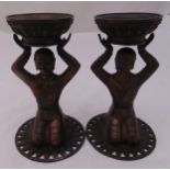 A pair of Tibetan bronze figural candle holders on pierced circular bases, 23cm (h)