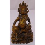 A Tibetan gilded bronze Buddha holding a mythical beast on raised oval base, 18.5cm (h)