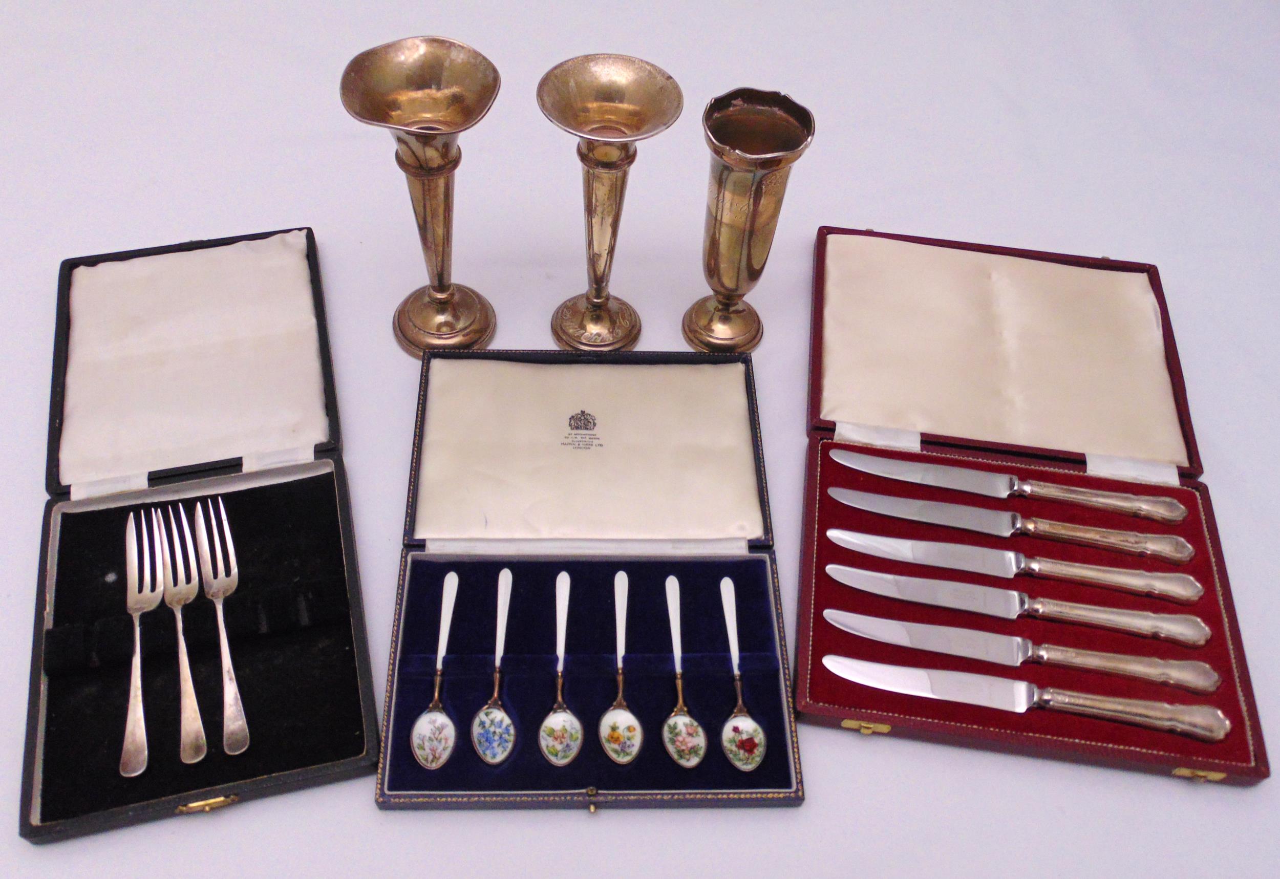 A quantity of hallmarked silver to include enamelled teaspoons, butter knives and three vases