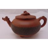 An unglazed Chinese terracotta teapot compressed cylindrical form, scroll handle and mask spout with