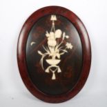 A Japanese oval lacquer panel, circa 1900, with applied carved bone decoration, in red lacquer