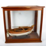 A small model rowing boat in glazed laboratory scales case, case height 44cm