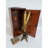 A Victorian brass binocular microscope, with a box of slides and extra fittings,