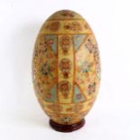 A large Oriental painted and gilded porcelain egg on hardwood stand, height 50cm