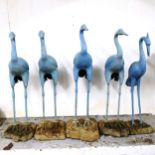 A set of 4 painted cast-iron heron bird garden sculptures, on concrete bases, and another similar