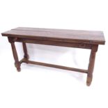 A narrow rectangular oak dining table, with double fold-out top, on H-shaped stretcher and