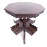 A Victorian carved oak book table, with octagonal top and rotating shelf below, on tripod base,