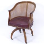 An early 20th century red leather upholstered and cane-backed bow-arm desk chair