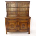 An oak dresser with boarded open plate rack, with 2 frieze drawers, and carved and panelled cupboard