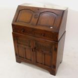 A linenfold carved and panelled oak bureau with cupboard doors, W77cm, H101cm, D41cm