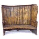 A large Antique stained pine bow-back settle, H140cm, L165cm