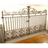 A large pair of decorative scrolled wrought-iron drive gates, width not including hinged mounts