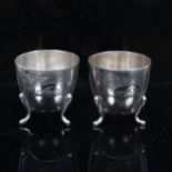 A pair of Continental silver egg cups, with engraved lion decoration on 3 feet, stamped 800