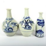 3 Japanese blue and white sake bottles with floral designs, tallest 27cm