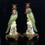 A pair of porcelain parrot figure candlesticks with scrolled brass plinths and sconces, height 36cm